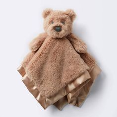 a teddy bear wrapped in a blanket on top of a white surface with no one around it