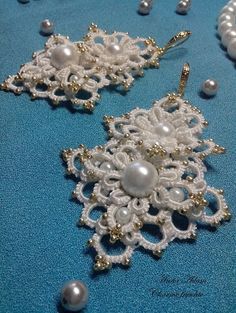 two pieces of white beaded jewelry on a blue surface with pearls and other beads