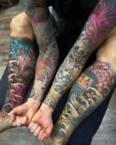 two men with tattoos on their arms and legs, both holding each other's hands