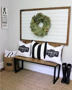 a wooden bench with two black and white pillows on it, sitting in front of a wall