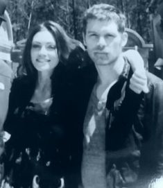 a man and woman standing next to each other in front of a group of parked cars