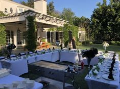 an outdoor dining area with tables and chairs set up in front of a large house