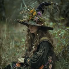 a woman wearing a witches hat sitting on the ground with her hands in her pockets