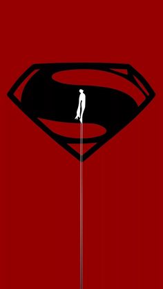 a man standing on top of a pole in front of a superman logo