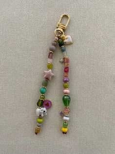 a key chain with beads and charms hanging from it's side on a white surface