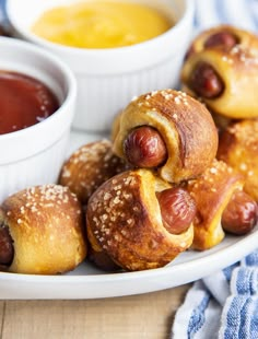 hot dogs wrapped in buns on a plate with dipping sauce