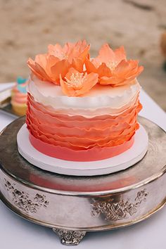 an orange and white layered cake with flowers on the top is ready to be eaten