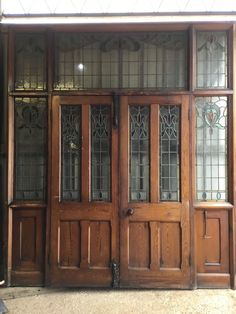 two wooden doors with glass panels in front of a building