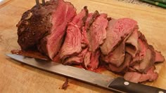 a large piece of meat sitting on top of a cutting board next to a knife