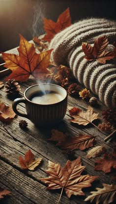 a cup of coffee sitting on top of a wooden table surrounded by leaves and cones