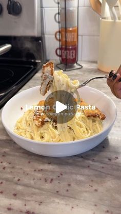 a person is eating spaghetti in a bowl on the kitchen counter with utensils