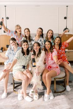 a group of women sitting next to each other in front of a tv holding wine bottles