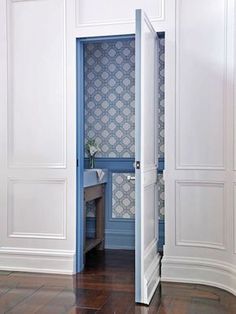 an open door leading into a bathroom with blue and white wallpaper