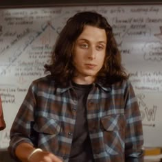 a woman standing in front of a whiteboard with writing on it and holding a knife