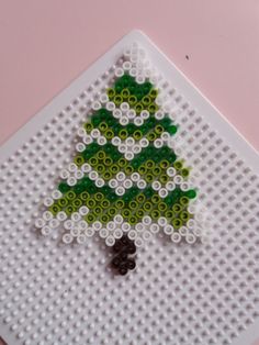 a christmas tree made out of legos on top of a white plate with green and black beads