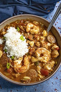 a bowl filled with shrimp and rice on top of a blue cloth next to a spoon