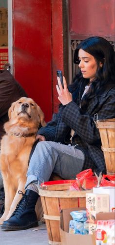 a woman is sitting on the street with her dog and looking at her cell phone