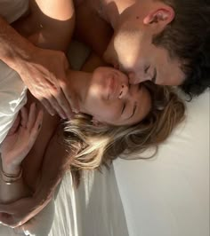 a man and woman laying on top of a bed next to each other with their eyes closed