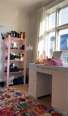 a room filled with lots of shoes and a desk in front of a large window