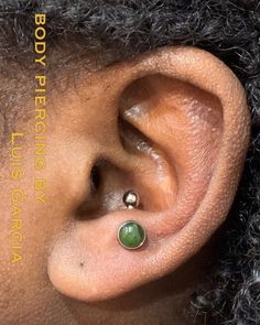 a close up of a person's ear with a green stone in the middle