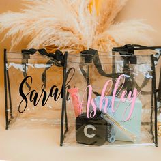 two clear bags with black handles and pink letters on the front, one has a name tag that says sara & ashley