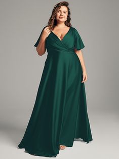 a woman in a long green dress posing for the camera with her hands on her hips