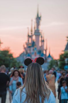 the back of a woman's head with ears in front of a castle at sunset