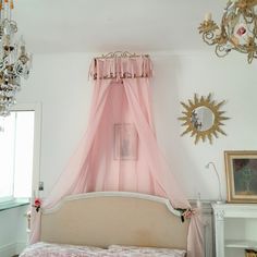 a pink canopy bed in a bedroom with chandelier