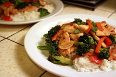 a white plate topped with rice and broccoli next to another plate filled with chicken