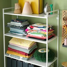 a white shelf filled with lots of different types of cloths and fabrics on top of it