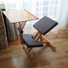 a wooden desk with a black chair next to it on top of a hard wood floor