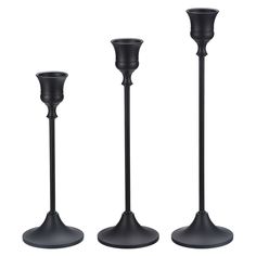 three black candlesticks sitting next to each other