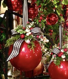 christmas decorations hanging from the ceiling in front of a tree with red and white ornaments