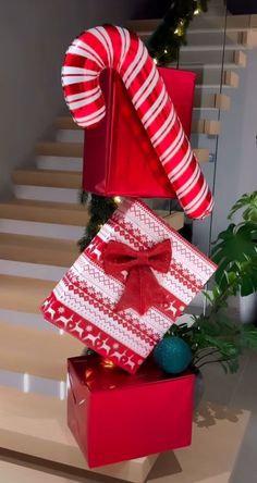 two wrapped presents sitting on top of each other in front of some stairs with christmas decorations