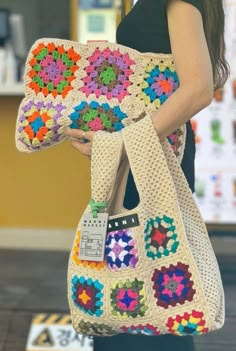 a woman carrying a crocheted bag with flowers on the front and bottom part