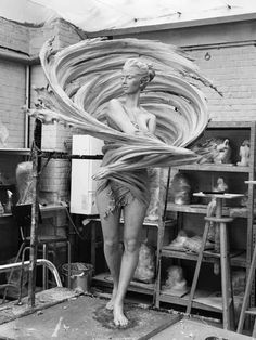 a woman standing on top of a wooden table holding a large object in her hands