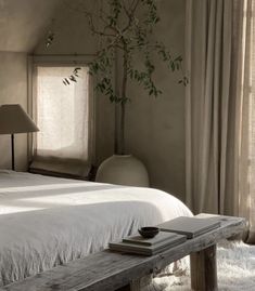 a white bed sitting next to a wooden table with a lamp on top of it