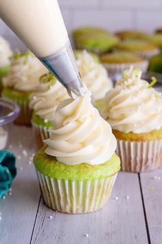 a cupcake being frosted with icing and sprinkles on a table