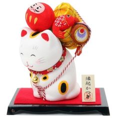 a white cat figurine with red and yellow decorations