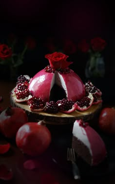 a red cake with white frosting and pomegranates on a plate