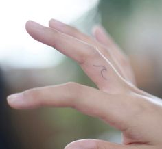 a person's hand with a small wave tattoo on the middle of their palm