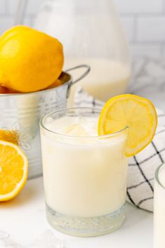 a glass of milk and some lemons on a table