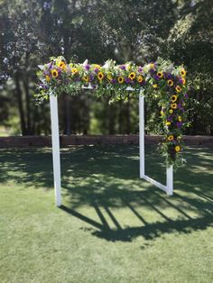 an outdoor wedding ceremony setup with sunflowers and greenery on the side of the aisle