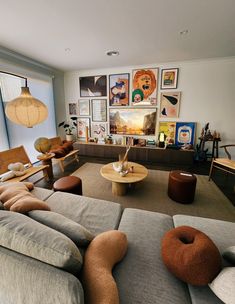 a living room filled with lots of furniture and pictures on the wall above it's windows