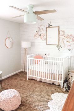 a baby's room is decorated in pink and white with flowers on the wall