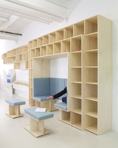 a person sitting on a bench in a room filled with bookshelves and benches