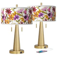 two lamps with flowers on them next to a phone