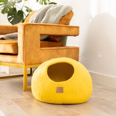 a yellow cat bed sitting on top of a hard wood floor next to a chair