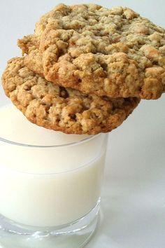 two oatmeal cookies sitting on top of a glass of milk