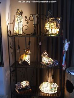 the cat shop is selling stained glass cats and lamps in their display cases, along with other decorative items